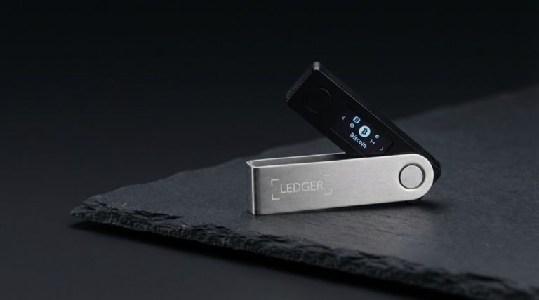 Ledger Nano X hardware wallet on dark slate surface with dramatic studio lighting showing brushed metal casing and OLED screen