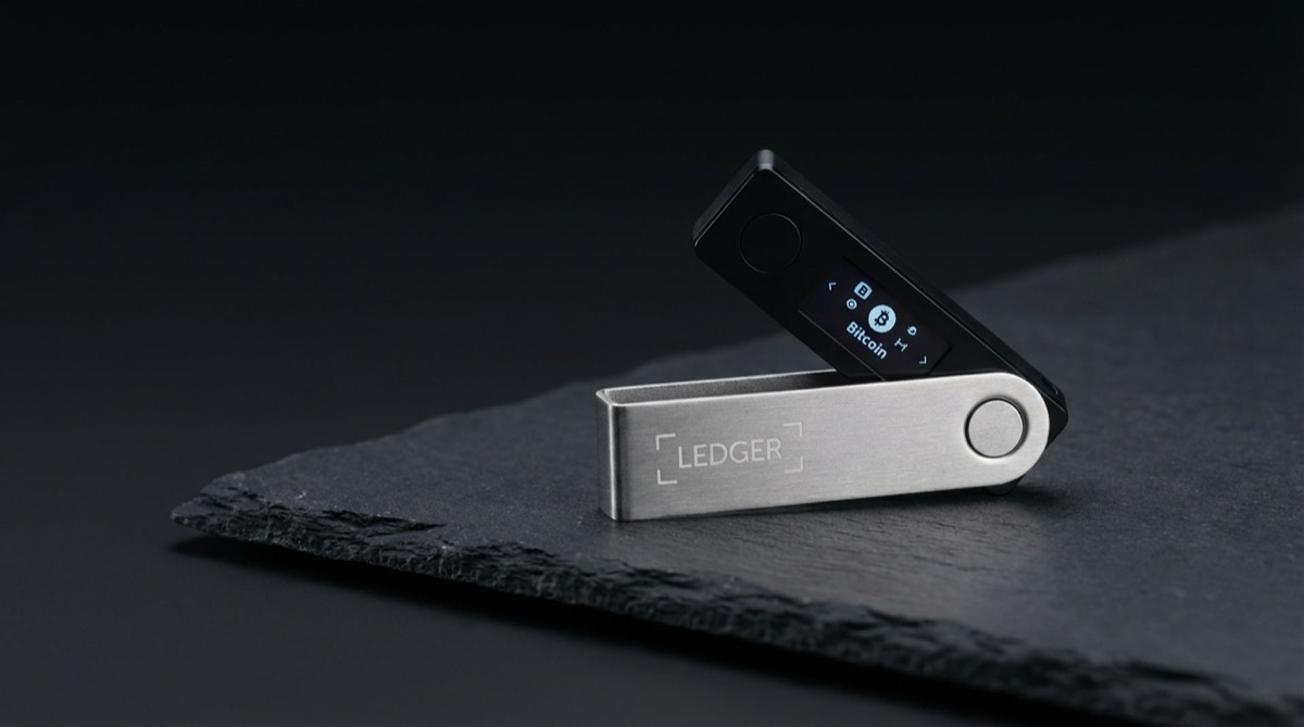 Ledger Nano X hardware wallet on dark slate surface with dramatic studio lighting showing brushed metal casing and OLED screen